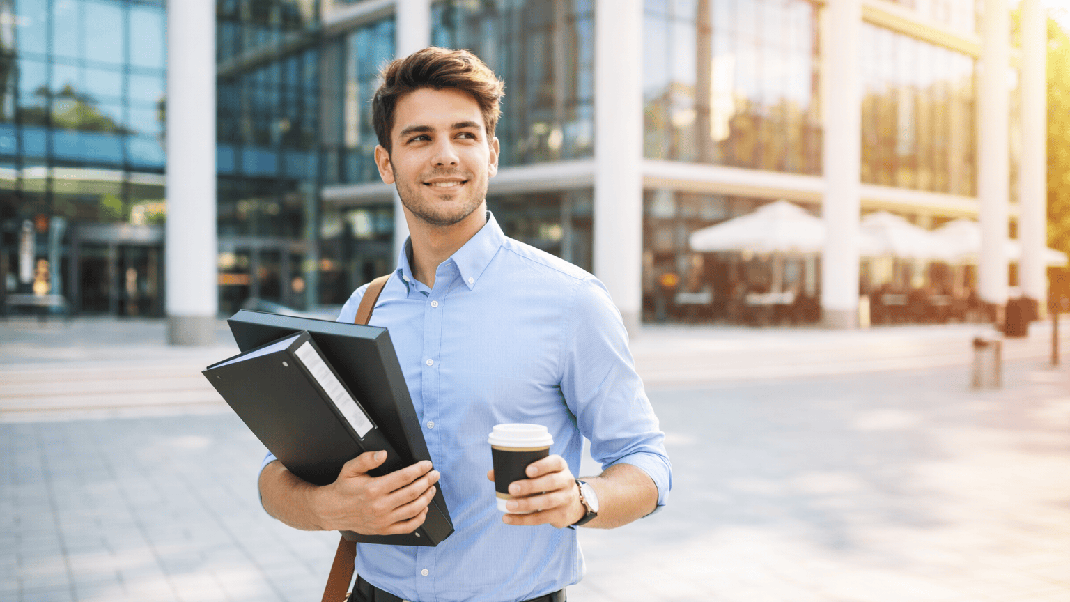 Business professional holding documents and coffee.